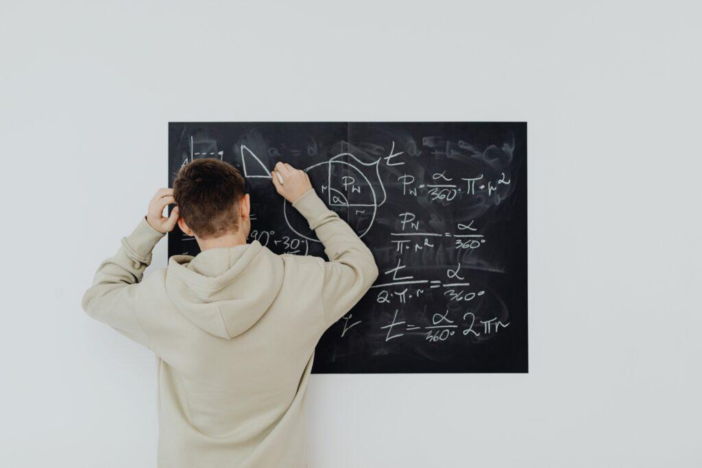 Alumno  delante de una pizarra con problemas matemáticos